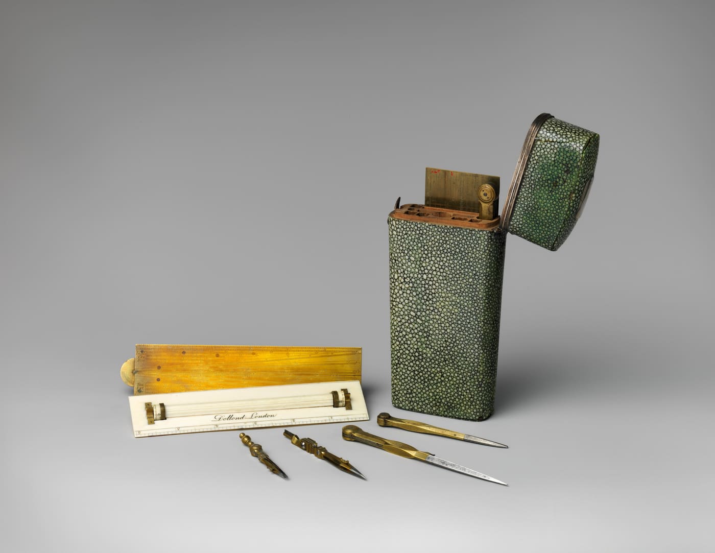 An eighteenth-century green shagreen case standing open, with its brass and ivory rulers, dividers and ruling pens laid out beside it.